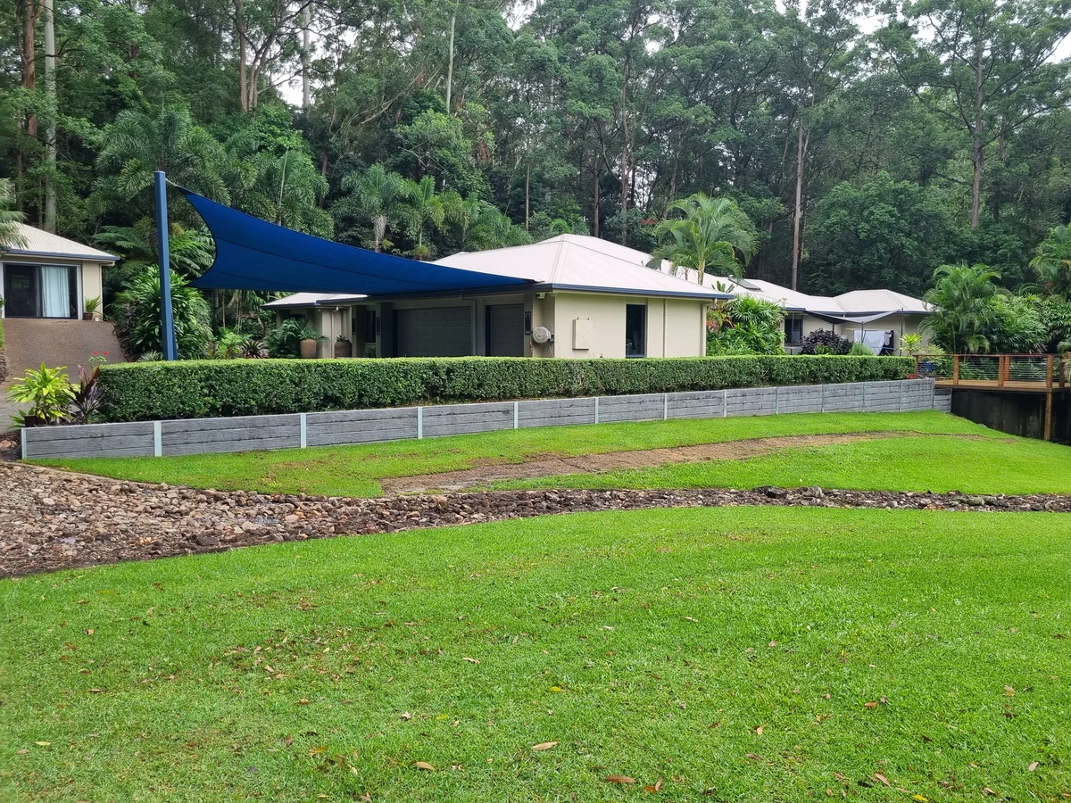Grey retaining wall beside a lawn and hedge at a Tanawha property